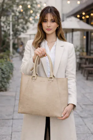 A woman carrying the Emlonc Fortelle Large Tote in beige vegan leather, styled on a city street beside a café