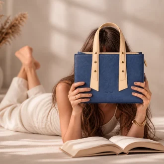 Woman holding EMLONC Vespera tote bag in navy blue and beige vegan leather during a relaxed everyday lifestyle setting
